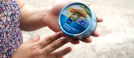 Thai Union Manufacturingin (TUM) työntekijä pitää kadessään Thai Unionin valmistamaa tonnikalapurkkia. Kuva: Finnwatch.